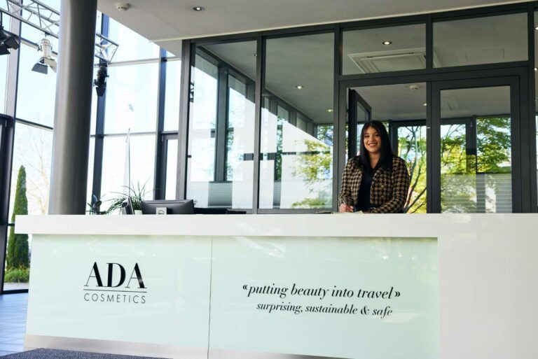 ADA Cosmetics reception desk with company logo and tagline: putting beauty into travel, surprising, sustainable & safe.