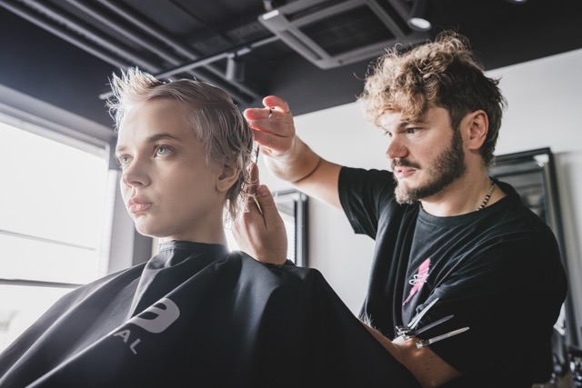 L'Oréal Professionel hairdresser cutting a client's short platinum hairstyle in a partner salon.