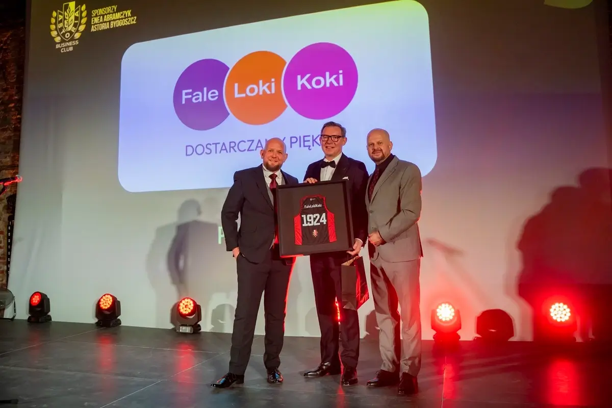 Fale Loki Koki team receiving an award on stage, with the company's three-circle purple, orange and magenta logo projected on the backdrop.