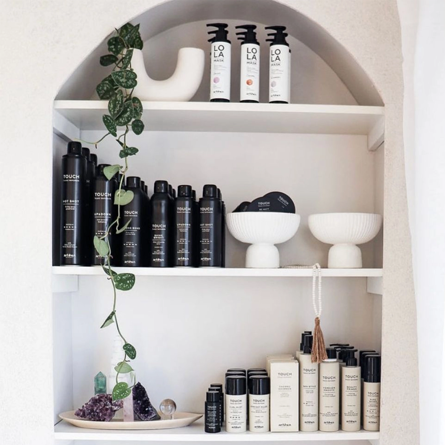 Curated wall shelf display pairing Lola from Mexico and Innersense Touch haircare products with vinyl plants and crystals.