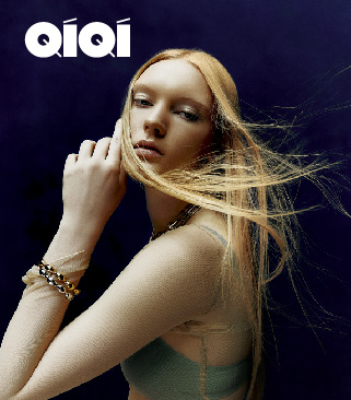 QiQi brand campaign: a model with long flowing blonde hair and gold cuff bracelet, set against a deep navy background with the QiQi wordmark at top left.